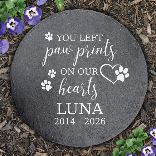Round slate stone with engraved text on a mulched surface with flowers