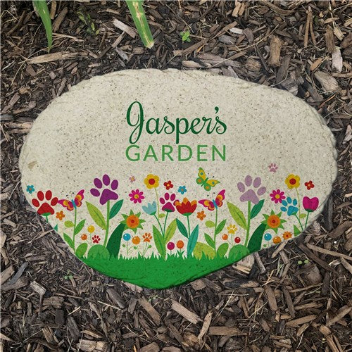 Decorative stone with 'Jasper's Garden' text and floral design on mulch