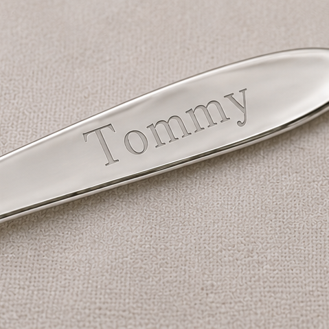 Silver spoon with 'Tommy' engraved on a beige background