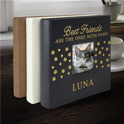 Book with a cat photo and text 'Best Friends are the ones with paws' on a wooden surface.