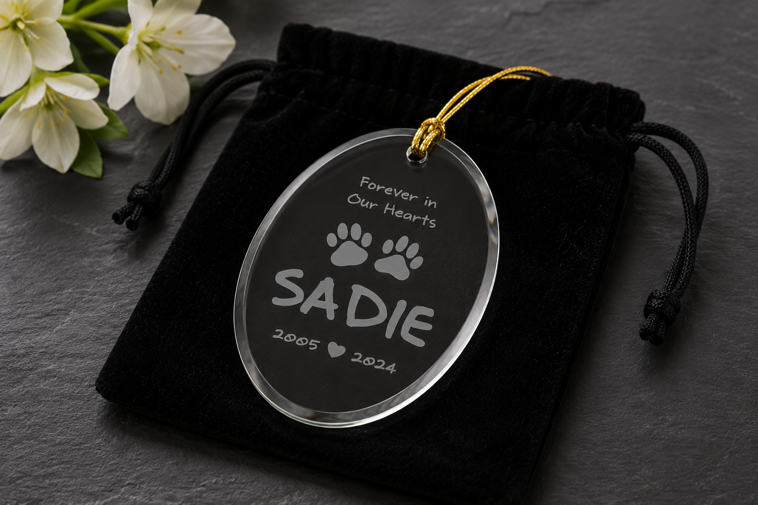 Memorial ornament for a pet named Sadie with paw prints and text on a dark background.